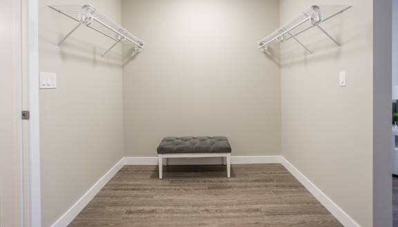 A room with a bench and two shelves on the wall.