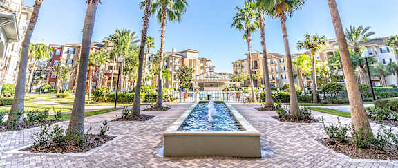A fountain surrounded by palm trees in the middle of a courtyard.