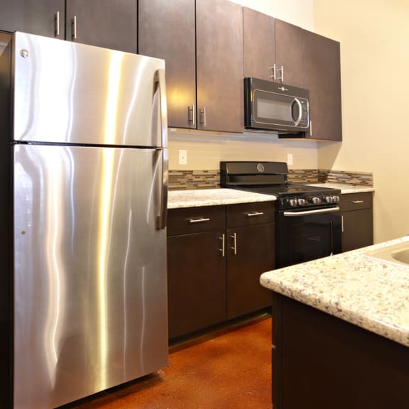 a kitchen with stainless steel appliances and black cabinets at Urban Square, Denton, TX, 76210