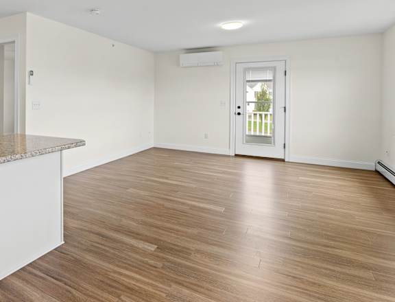 a renovated living room and kitchen with white walls and wood floors