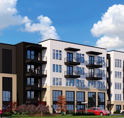 A large apartment complex with multiple balconies and a parking lot in front.