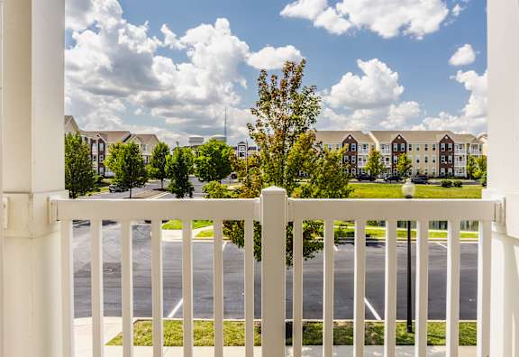 A white fence in front of a road with apartment buildings in the background.