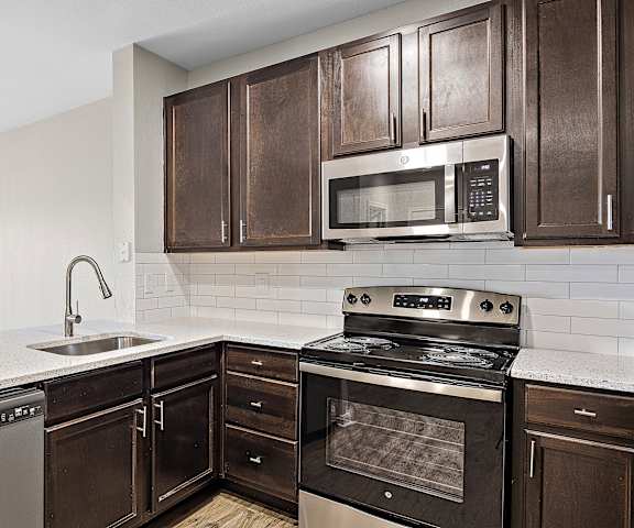 a kitchen with dark wood cabinets and white countertops at Las Brisas Apartment Homes, Round Rock, TX