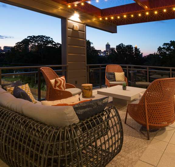 a covered patio with wicker chairs and a table and lights