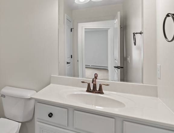 A white bathroom with a toilet, sink, and mirror.