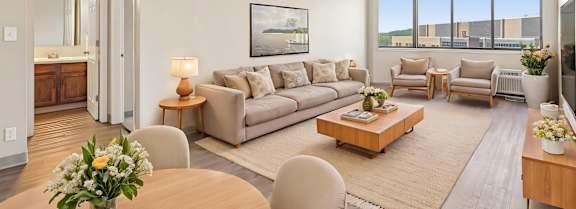 Virtually staged Irvine Park Towers living room with sofa, dining table and seating near large windows