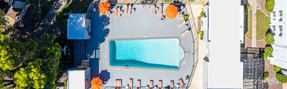 An aerial view of a pool surrounded by orange chairs and trees.