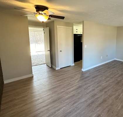 an empty living room with wood floors and a ceiling fan