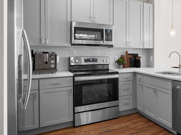 A modern kitchen with wooden floors and stainless steel appliances.