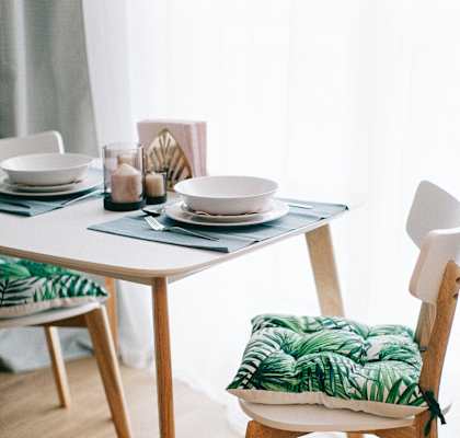 White kitchen table with a blue placemat and white dishes place setting. 