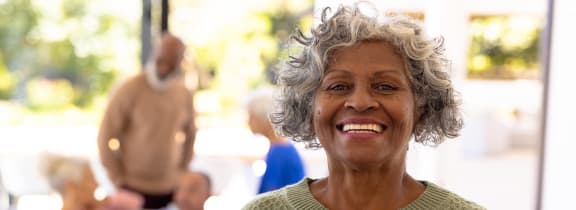 a smiling older woman standing in front of a group of people