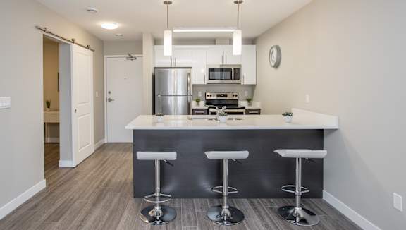 A modern kitchen with a bar stool in front of the island.