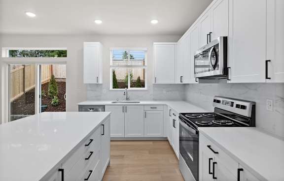 A modern kitchen with white cabinets and appliances.