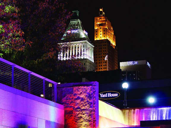 A colorful light display at a waterfall in front of a building.