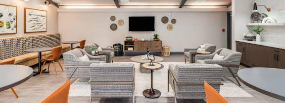 A modern living room with a grey sofa set, a white coffee table, and a TV mounted on the wall.