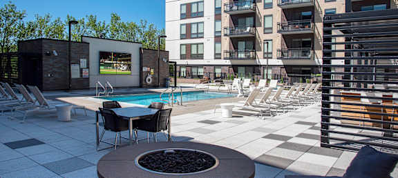 A modern outdoor pool area with a hot tub and lounge chairs.