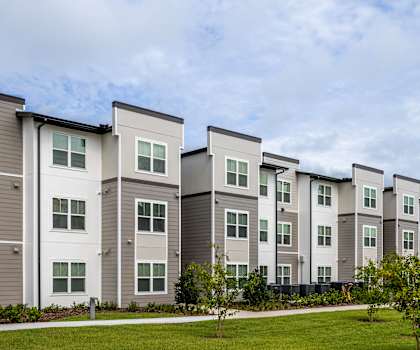 Apartment complex with grey and white buildings and green lawns.