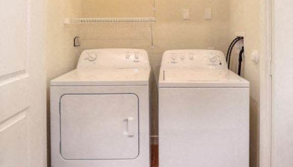 Two white front loading washing machines in a small laundry room.