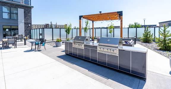 A modern outdoor kitchen area with a grill and seating area.