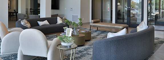 A spacious living room with a grey sofa and a wooden floor.