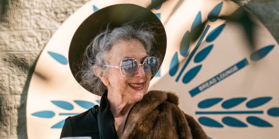 a woman in a hat and a fur coat holding a cup of coffee
