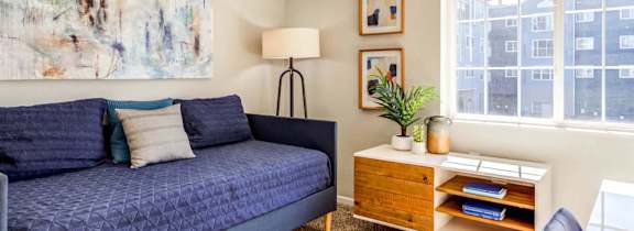 A living room with a grey couch, a coffee table, and a painting on the wall.