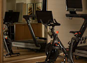 Thumbnail 18 of 30 - A room with a treadmill, a stationary bike and a computer monitor at The PARKER on E Mulberry Apartments, Texas