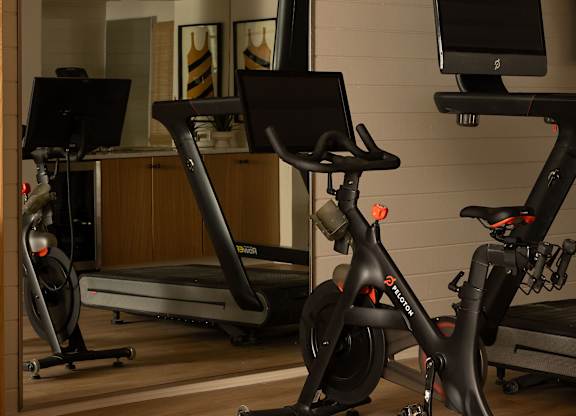A room with a treadmill, a stationary bike and a computer monitor at The PARKER on E Mulberry Apartments, Texas