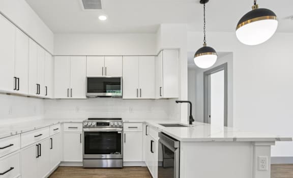 A modern kitchen with white cabinets and a wooden floor.