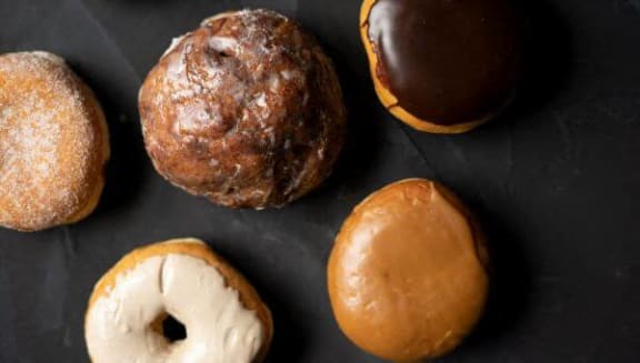 a group of different donuts on a black table
