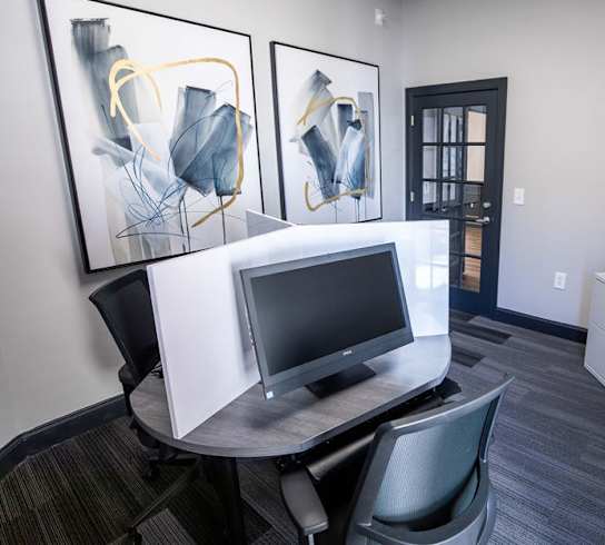 A room with a desk, chair, and two framed artworks on the wall.