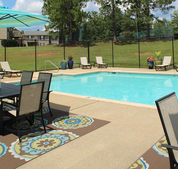 A pool surrounded by chairs and umbrellas.