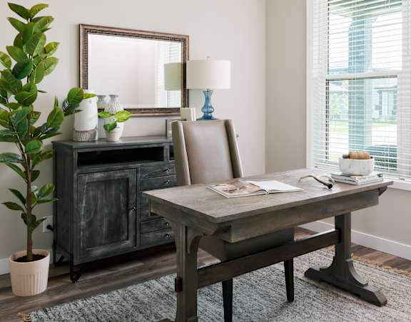 A room with a desk, chair, and a mirror.