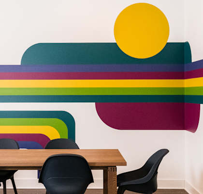 A dining room with a colorful wall mural and a wooden table with chairs.