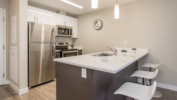 A kitchen with a white counter top and a stainless steel refrigerator.