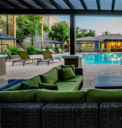 A patio with a pool and green couches.