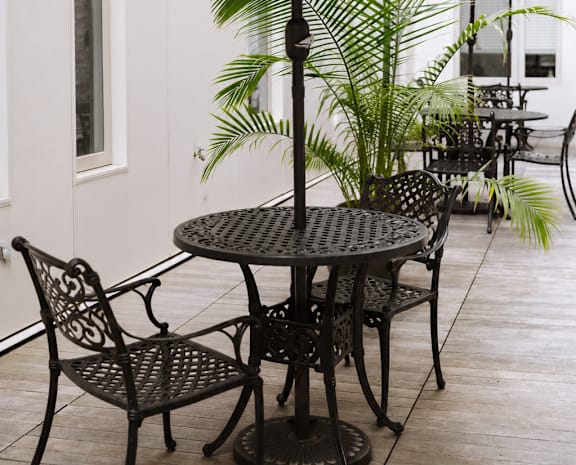 A table with chairs and an umbrella is on a patio.