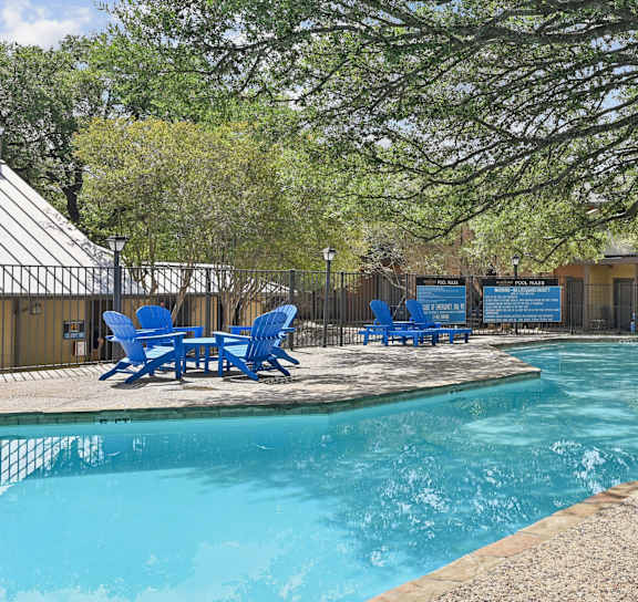 A large tree shades a swimming pool.