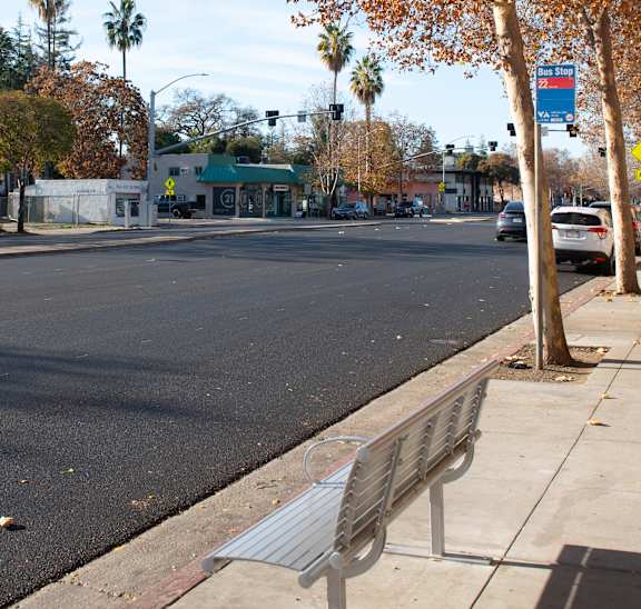 A street with a bench on the sidewalk.