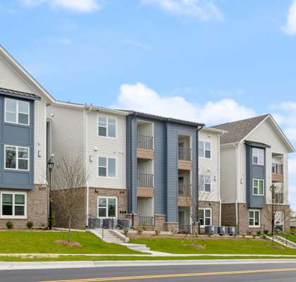Apartment building on a street corner with a clear blue sky.