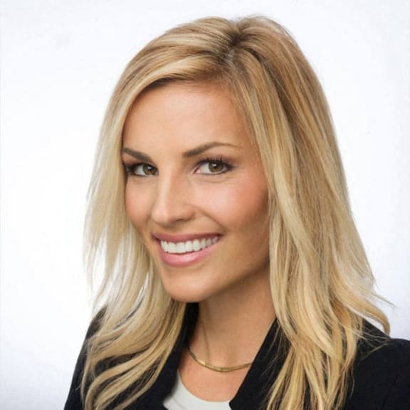 a woman with long blonde hair wearing a black jacket and a white shirt