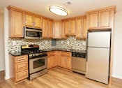 Thumbnail 1 of 23 - A kitchen with wooden cabinets and a black and white tiled backsplash at Potomac Ridge Apartments, Woodbridge, 22191