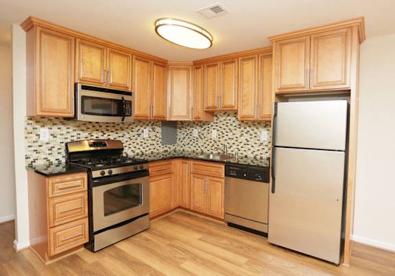A kitchen with wooden cabinets and a black and white tiled backsplash at Potomac Ridge Apartments, Woodbridge, 22191