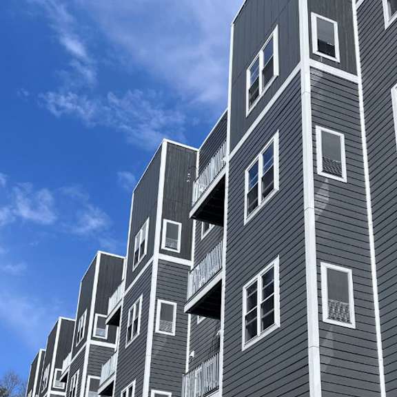 A tall building with grey siding and white windows.