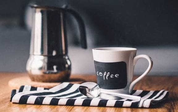 A coffee mug on a table with a spoon beside it.