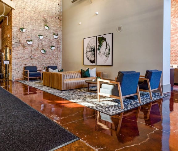 a living room with a couch and chairs and a brick wall