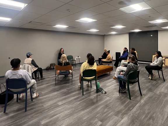 A group of people are sitting in a circle in a room at The Nines Apartments in Allentown, PA
