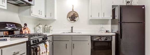 A kitchen with white cabinets and a black refrigerator.