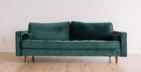 a green couch sitting on a wooden floor
