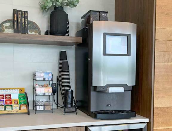 a coffee bar with an espresso machine, a mini fridge with drinks, and tea options in the front lobby